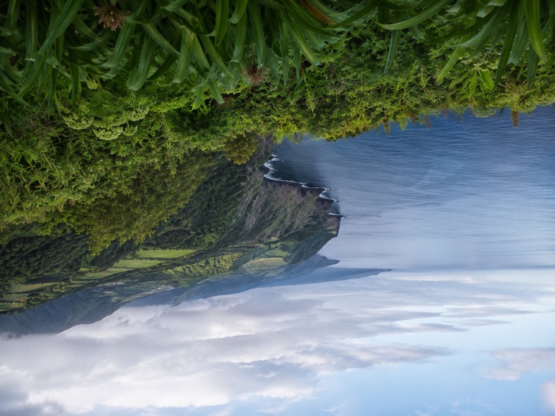 Grüne Atlantikküste mit Steilhang, Meerblick und milder Wolkenstimmung.